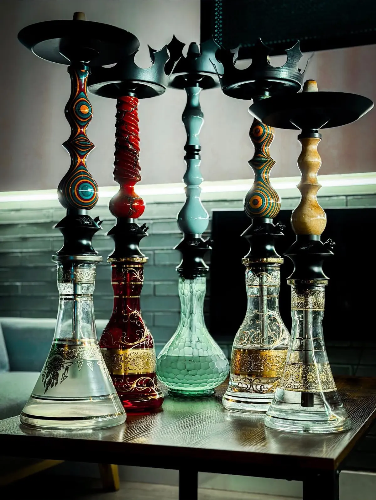 Cinco cachimbas en fila: mástiles de madera de colores y bases de cristal con dorados